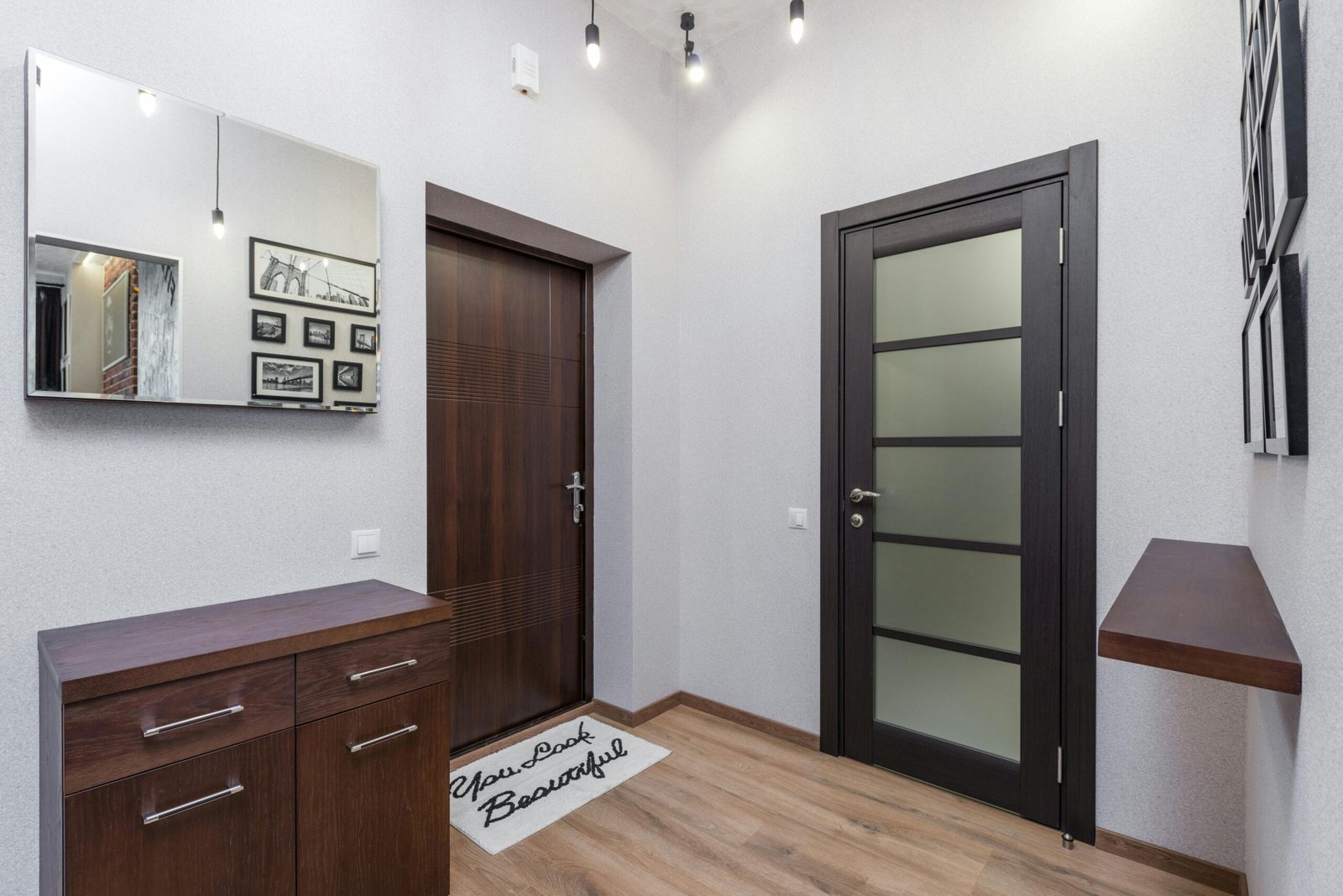 Stylish interior entryway featuring dark wood elements, a mirror, and framed art.